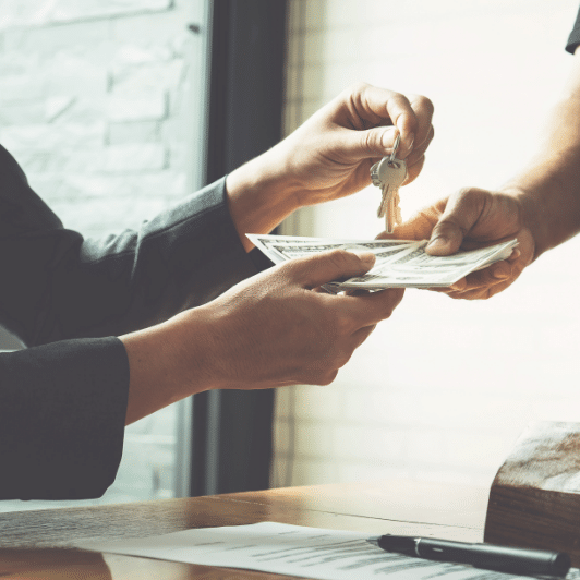 A warm-toned image of a realtor receiving cash in exchange for a set of house keys
